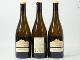 trois bouteilles de vin posées les unes à côté des autres sur une surface blanche