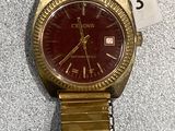 an image of a gold wrist watch with a red face