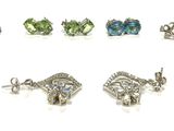 six pairs of earrings with different colored stones on a white surface