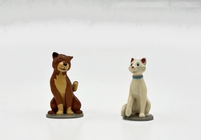 deux figurines de chats assis l'un à côté de l'autre sur une surface blanche