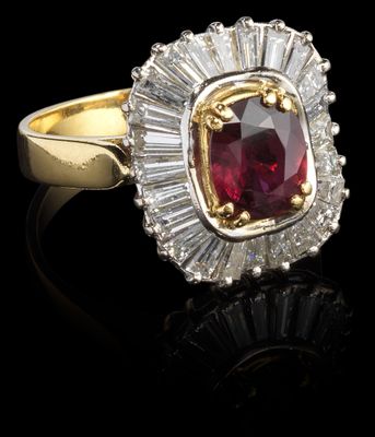 gros plan d'une bague avec une pierre rouge entourée de diamants blancs