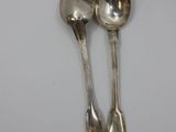 two silver spoons sitting next to each other on a table