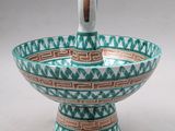 a close up of a bowl with a handle on a table