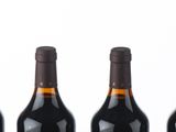 six bottles of red wine lined up in a row on a white surface