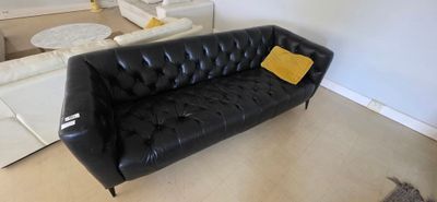 a black leather couch with a yellow pillow in a living room