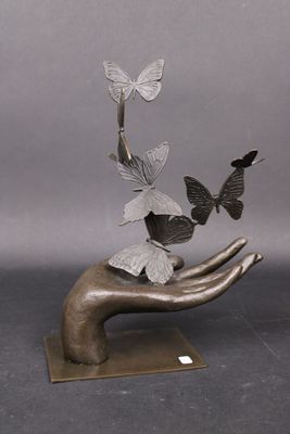une sculpture représentant une main tenant un bouquet de papillons