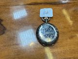 a small silver pocket watch on a wooden table