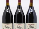 three bottles of red wine are lined up on a white surface