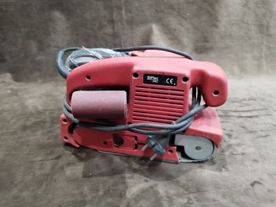 une ponceuse rouge posée sur une surface grise