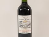 the bottle of red wine is sitting on a white surface