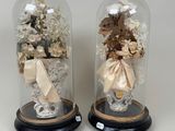deux cloches en verre contenant des fleurs