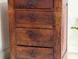 an image of a wooden chest of drawers with a plant in the corner