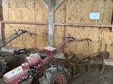 un tracteur garé dans une grange, avec une charrue attelée