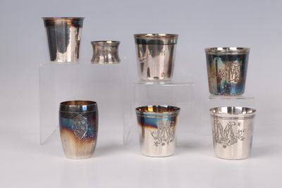 several silver cups and cups with designs on them on a table