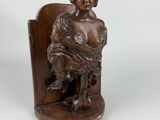 an image of a wooden statue of a woman sitting on a chair