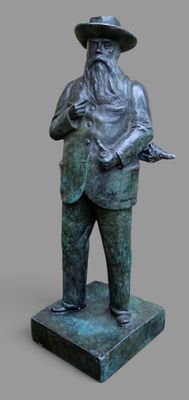 statue d'un homme portant un chapeau et une canne, debout sur un socle