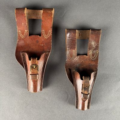two brown leather holsters on a gray surface