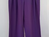 un pantalon violet suspendu à un cintre devant un mur blanc