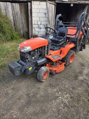 un petit tracteur orange garé devant une grange