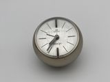 a silver clock sitting on a white surface