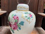 a white vase with pink flowers on it sitting on a table