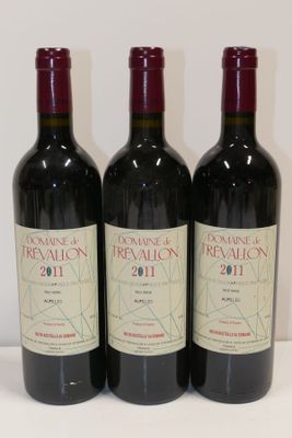 trois bouteilles de vin rouge sont alignées sur une surface blanche