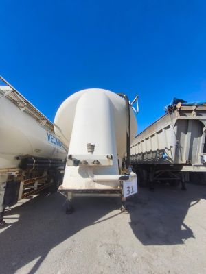 un homme debout devant un camion sur lequel est fixée une grande citerne à l'arrière
