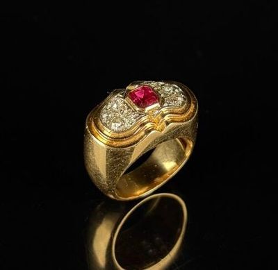 a close up of a gold ring with a red stone in it