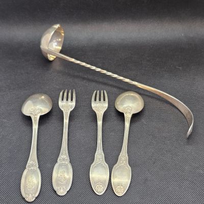 quatre cuillères en argent et une fourchette sont posées sur une surface noire