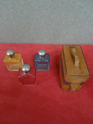 three small bottles of perfume on a red surface