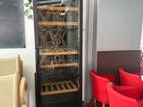 a wine cooler in the middle of a room with red chairs