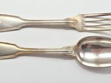 two spoons and a fork on a white surface