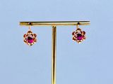 boucles d'oreilles ornées de pierres roses sur un support doré, se détachant sur un ciel bleu