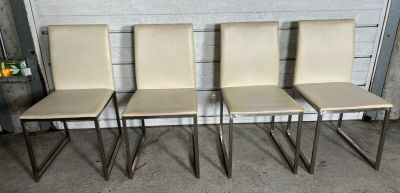 quatre chaises de salle à manger en cuir couleur crème avec des pieds chromés, dans un garage