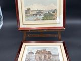 two framed pictures of buildings and a vase on a table