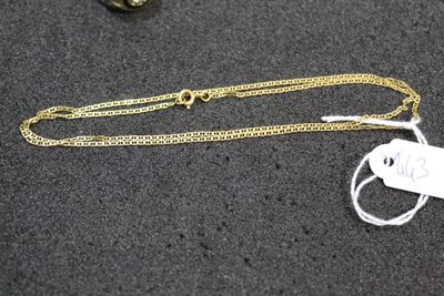 a gold chain with a tag on it next to a pair of scissors