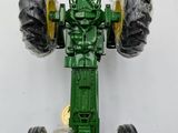 a green toy tractor with large tires on a white surface
