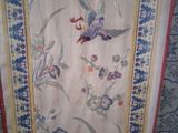 a picture of a wall hanging with a bird and flowers on it