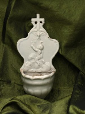 a white vase with a statue on it on a green cloth