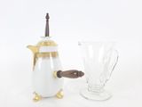 a white and gold coffee pot next to a glass vase