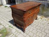 une petite commode posée sur un trottoir en briques