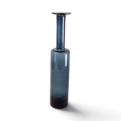un vase en verre bleu avec un couvercle noir posé sur une surface blanche