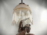 a statue of a woman laying on the ground with a lamp on her head