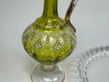 a green glass pitcher sitting on a table next to a glass plate