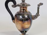 silver plated teapot with a black handle on a white background