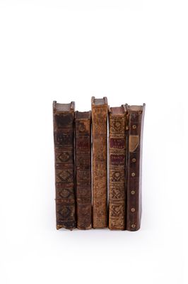 several old books are stacked on top of each other on a white surface