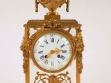 une horloge en or posée sur une surface blanche