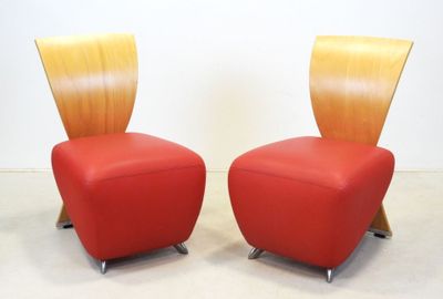 pair of red leather chairs with wooden legs in a white room