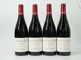 quatre bouteilles de vin sont alignées sur une surface blanche