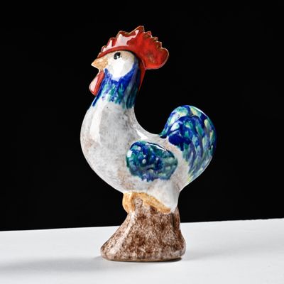 rooster figurine on a white surface against a black background